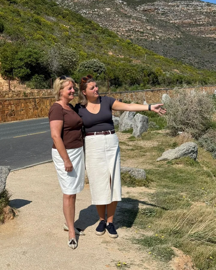 Joyce en Mirte langs de kustweg bij Kaapstad, Mirte wijst iets aan